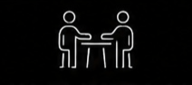 Two simple stick figures sitting opposite each other at a table on a black background.